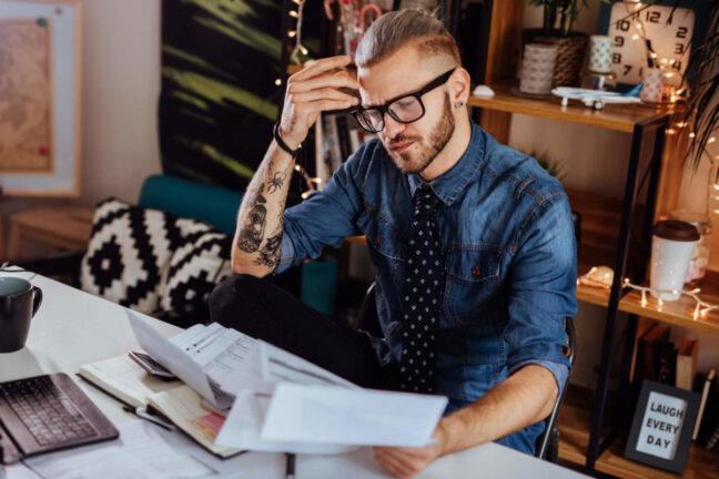 Millennial sits in front of a computer with financial documents.