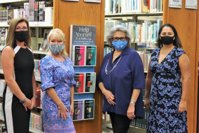 Women posing with booklets at the PBC library